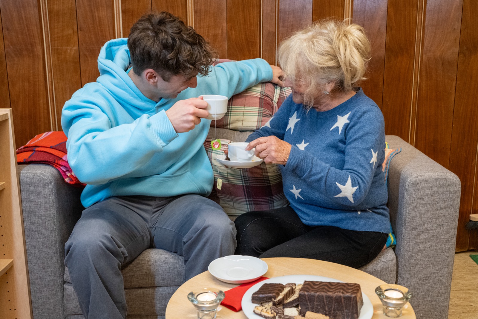 Junger Alltagshelfer und Seniorin trinken gemeinsam Kaffee